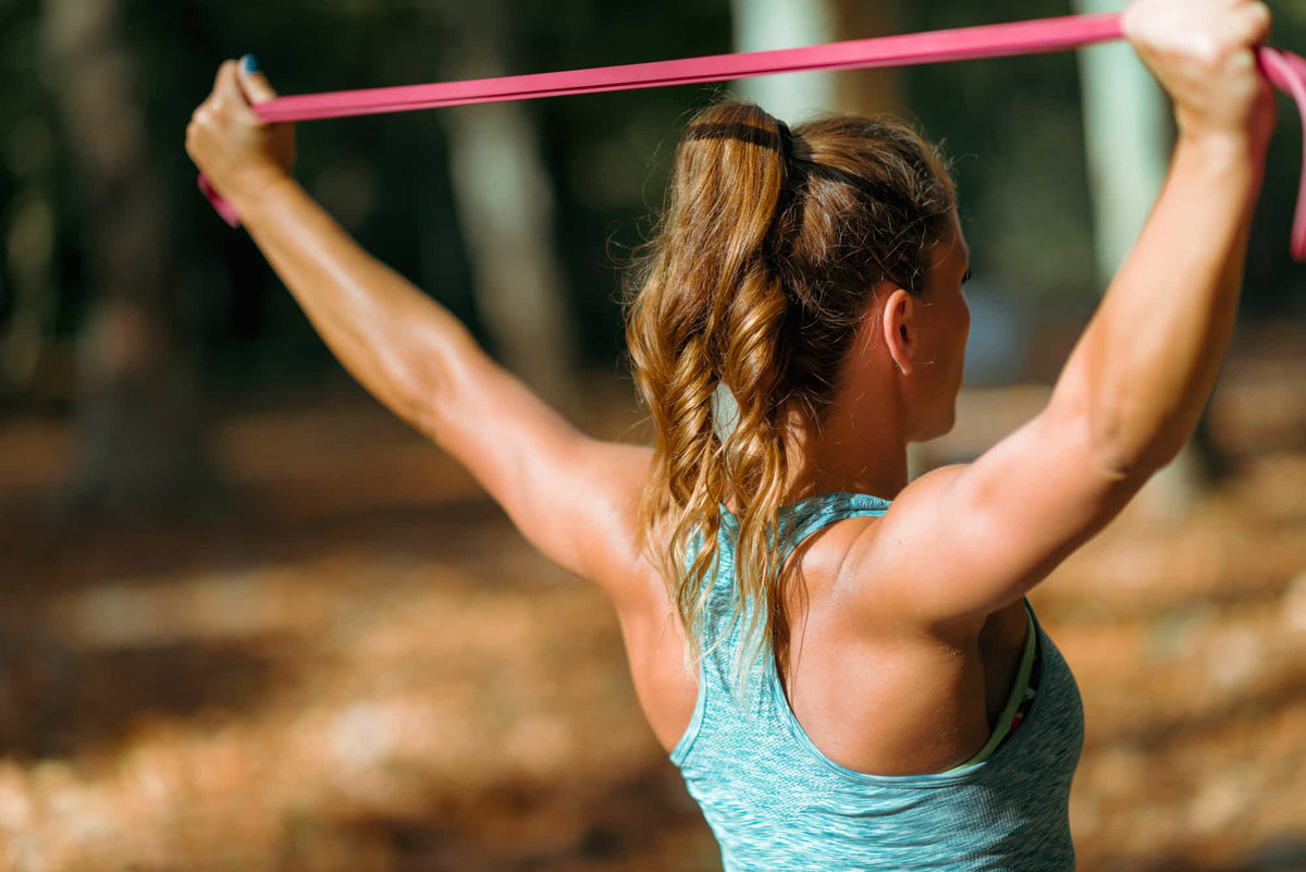 Woman performing an overhead resistance band exercise outdoors