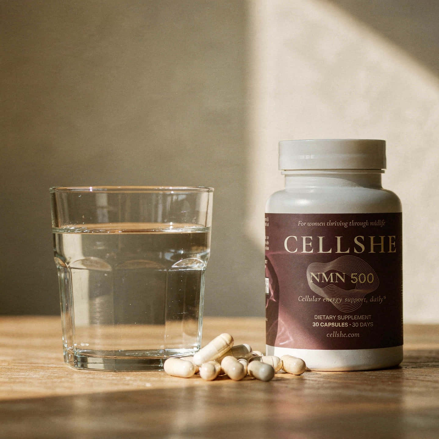 CELLSHE NMN 500 supplement bottle with capsules and a glass of water