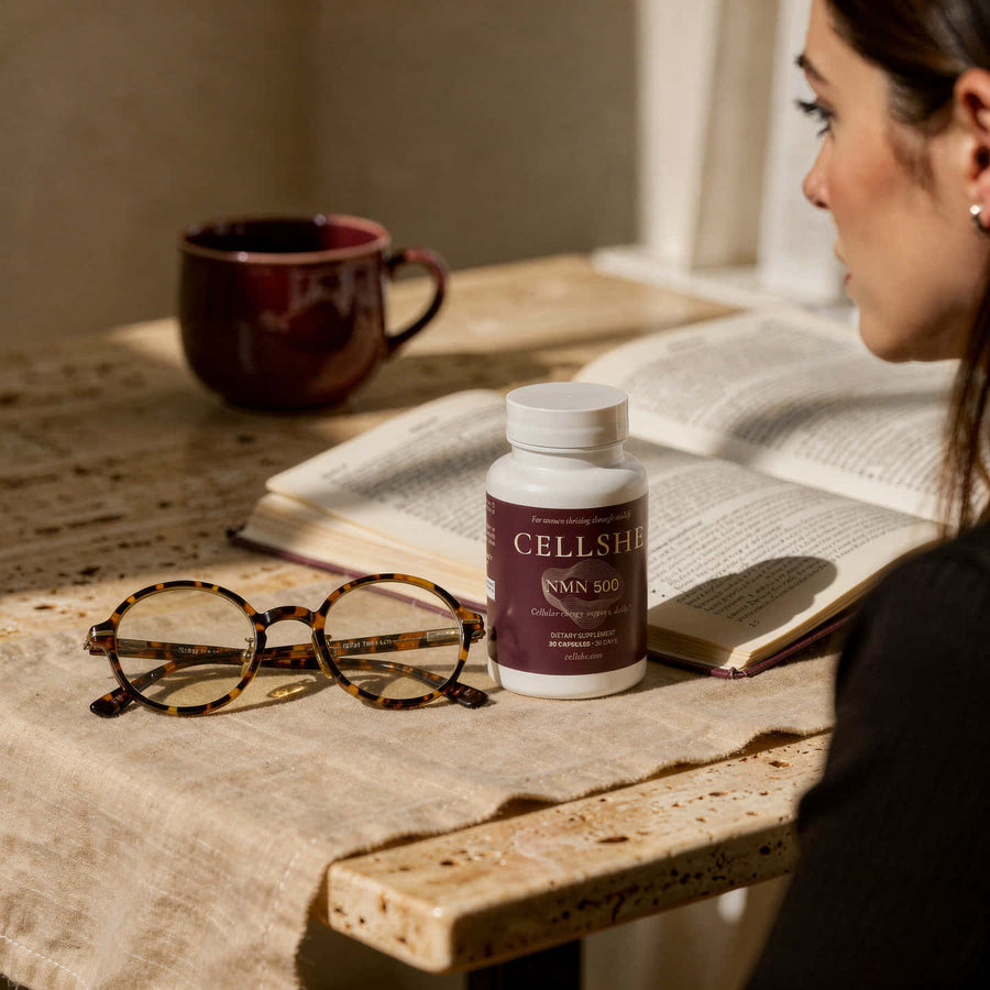 A woman reading beside a CELLSHE NMN 500 bottle and an open book
